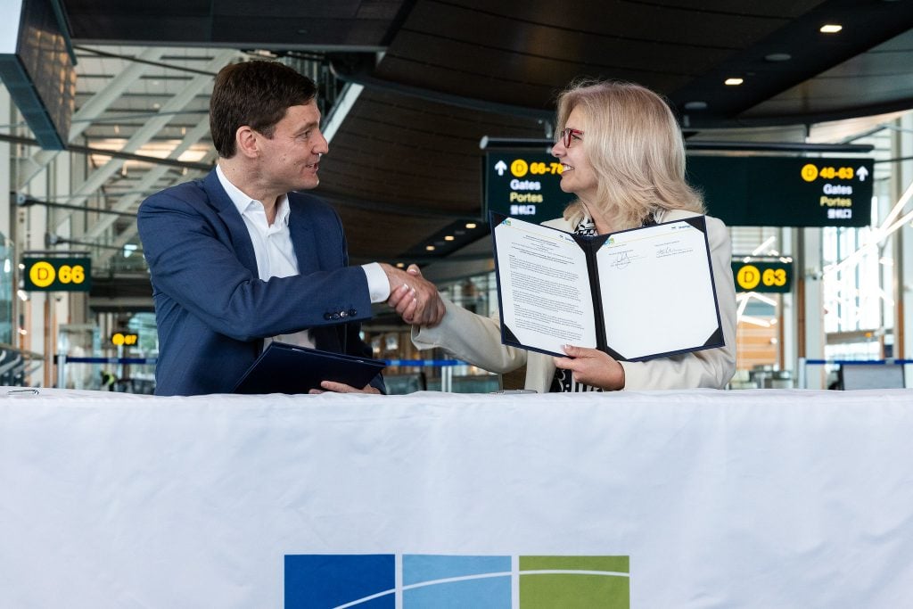 Le premier ministre, David Eby, et la directrice générale de YVR, Tamara Vrooman, se serrent la main.